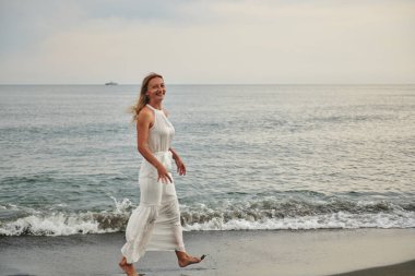 Sahilde beyaz elbiseli neşeli bir kız. Yüksek kalite fotoğraf