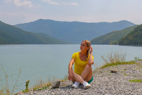 a girl is sitting on the shore of the Zhinvali reservoir. High quality photo