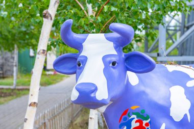 Çimlerin üzerinde çok renkli bir inek duruyor. Yüksek kalite fotoğraf