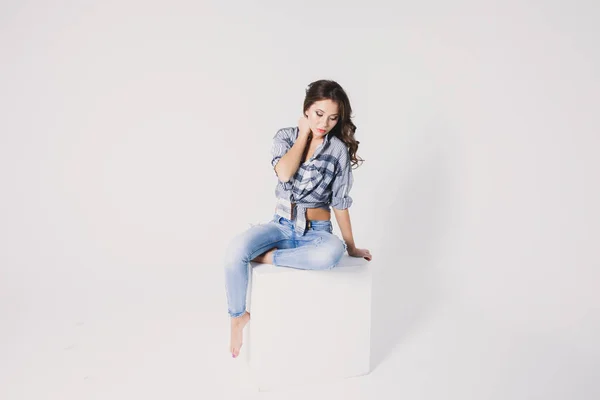 Uma Menina Uma Camisa Xadrez Jeans Senta Cubo Branco Fundo — Fotografia de Stock