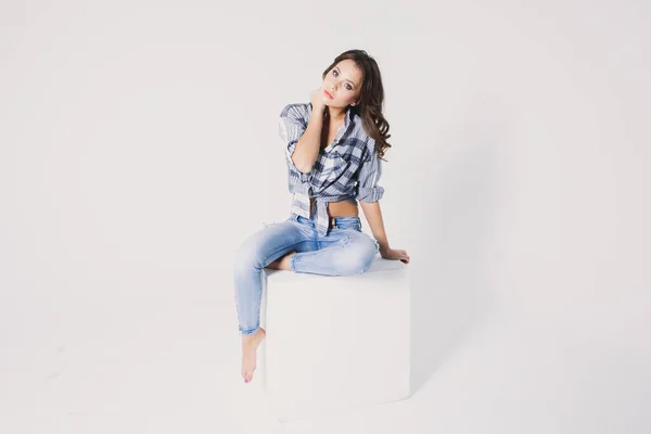 Uma Menina Uma Camisa Xadrez Jeans Senta Cubo Branco Fundo — Fotografia de Stock