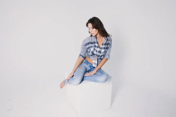 Uma Menina Uma Camisa Xadrez Jeans Senta Cubo Branco Fundo — Fotografia de Stock