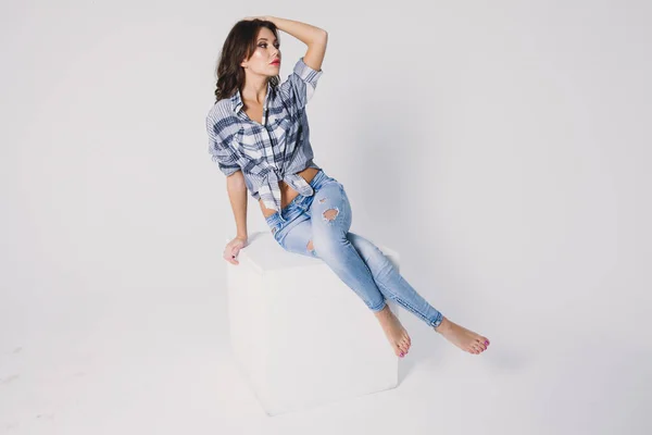 Ein Mädchen Kariertem Hemd Und Jeans Sitzt Auf Einem Weißen — Stockfoto