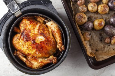 A whole chicken cooked inside an air frier concept. A healthy nutritious homemade alternative to deep fried store bought meat. Served inside the fryers basket together with baked potatoes. clipart