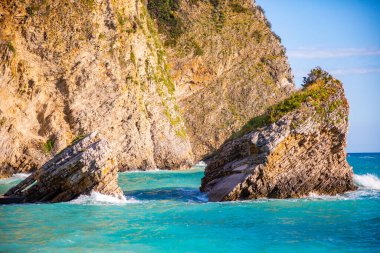 Karadağ 'ın Budva kentindeki Aziz Niklas adasındaki plaj ve uçurumlar. Denizde bir adadaki cennet kumsalı