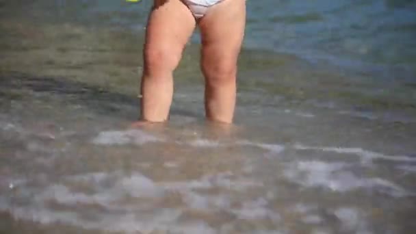 Baby child walking on a sandy beach splashing in water — Stock Video