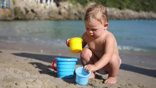 Klein meisje spelen met zand op het strand. Genieten van een heerlijke vakantie. — Stockvideo