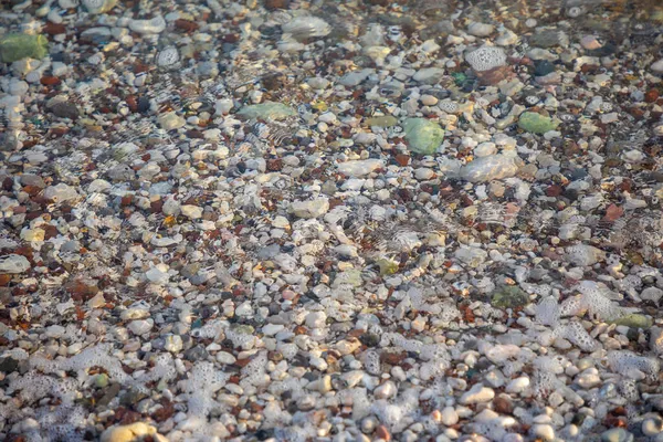 靠近水面的海滩上的湿石头的背景 — 图库照片