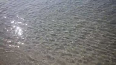 Kum deniz tabanının yüzeyindeki dalgalar berrak ve sakin mavi deniz suyu, sudaki balıklar, doğa dokusu.