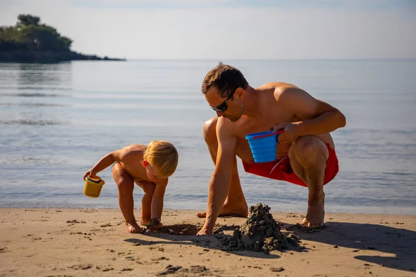 Padre e hija construyendo castillo de arena en la playa en un día soleado. — Foto de Stock