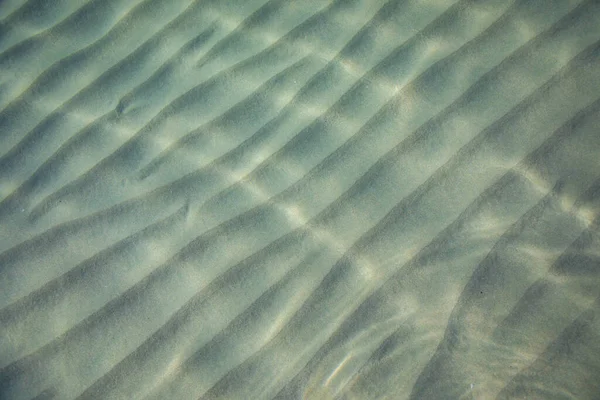 Kum deniz tabanının yüzeyindeki dalgalar berrak ve sakin mavi deniz suyu, sudaki balıklar, doğa dokusu. — Stok fotoğraf