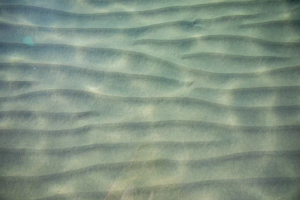 Ripples pe suprafața fundului mării de nisip, apă albastră limpede și calmă de mare, pești în apă, textura naturii — Fotografie, imagine de stoc