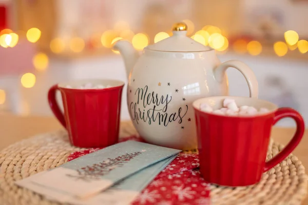 White Ceramic TeaPot with text Merry Christmas and cups with marshmallows on xmas bokeh background — Stock Photo, Image