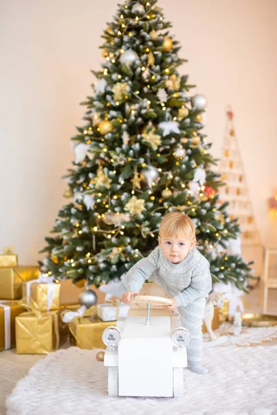 Menina adorável sentada perto da árvore de Natal com luzes festivas e presentes de xmas. Chrismas e Ano Novo. — Fotografia de Stock