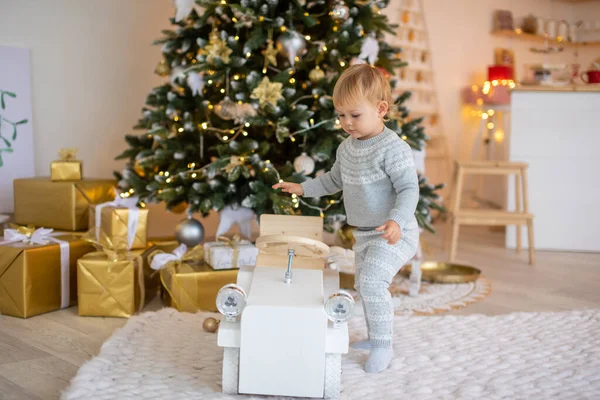 Adorable petite fille assise près du sapin de Noël avec des lumières festives et des cadeaux de Noël. Noël et Nouvel An. — Photo