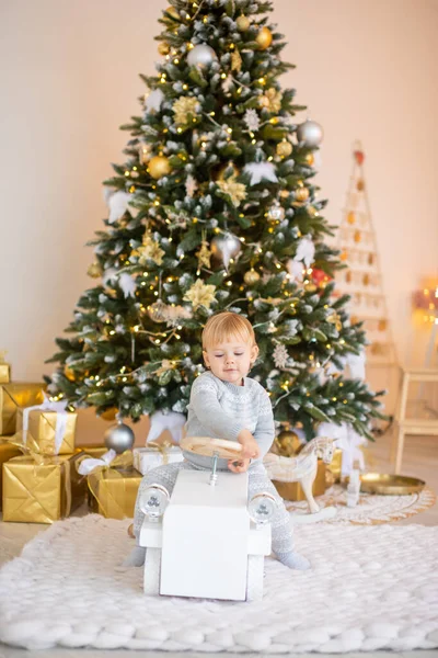 Noel ağacının yanında Noel ışıkları ve Noel hediyeleriyle oturan sevimli bir kız. Noel ve Yeni Yıl.