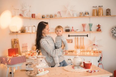 Mutlu komik anne ve çocuk küçük kız Noel süslenmiş mutfakta eğleniyor. 