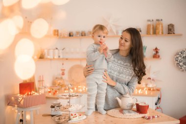 Mutlu komik anne ve çocuk küçük kız Noel süslenmiş mutfakta eğleniyor. 