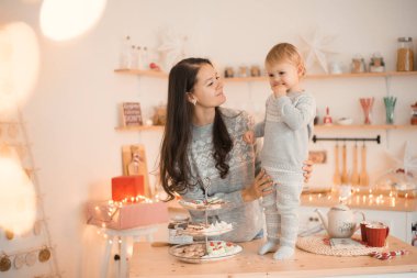 Mutlu komik anne ve çocuk küçük kız Noel süslenmiş mutfakta eğleniyor. 