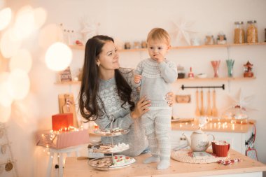Mutlu komik anne ve çocuk küçük kız Noel süslenmiş mutfakta eğleniyor. 