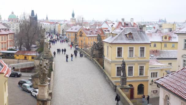 As pessoas estão andando na ponte Charles, cujos telhados estão cobertos de neve, Praga no inverno — Vídeo de Stock