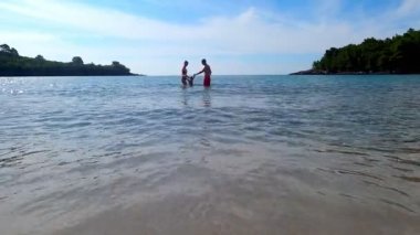 Happy family - father, mother and daughter having fun outdoors. Young joyful family with beautiful little girl in the sea