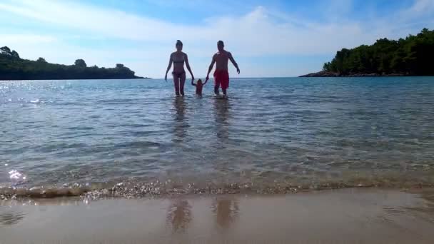 Familia feliz: padre, madre e hija se divierten al aire libre. Joven familia alegre con hermosa niña en el mar — Vídeos de Stock