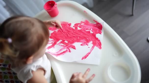 Schattig klein meisje dat thuis met vingers schildert. Creatieve spelletjes voor kinderen. Blijf thuis entertainment — Stockvideo