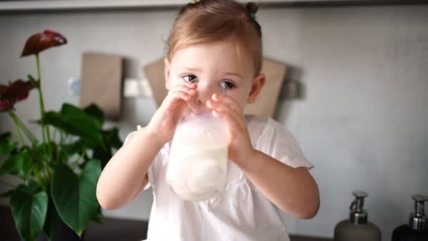 Šťastná holčička sedí u stolu v kuchyni a pije mléko — Stock video