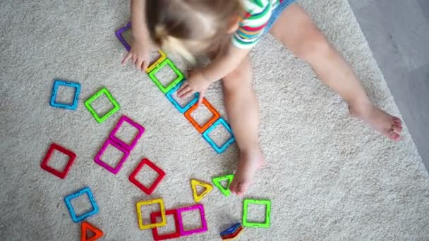 Маленькая девочка играет красочные пластиковые блоки магнит набор дома. Ребенок играет в образовательные игры. Раннее развитие детства. — стоковое видео