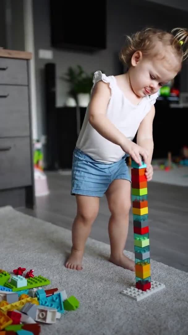 Enfant caucasien une petite fille joue dans le constructeur à la maison. Jouets éducatifs pour enfants. — Video