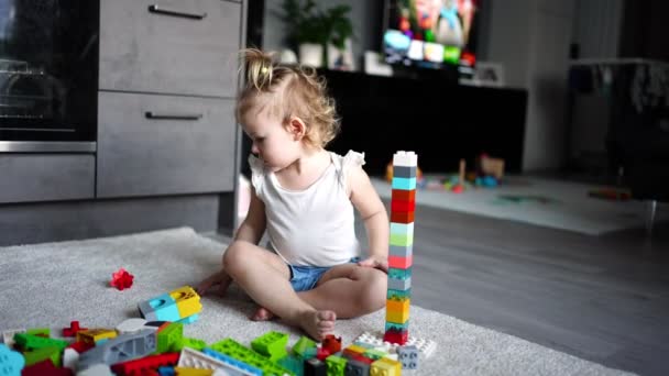 Bambino caucasico una bambina sta giocando nel costruttore a casa. Giocattoli educativi per bambini. — Video Stock