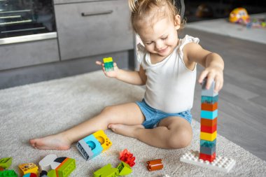 Beyaz bir çocuk evdeki inşaatçıda küçük bir kız oynuyor. Çocuklar için eğitici oyuncaklar.