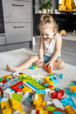 Beyaz bir çocuk evdeki inşaatçıda küçük bir kız oynuyor. Çocuklar için eğitici oyuncaklar.
