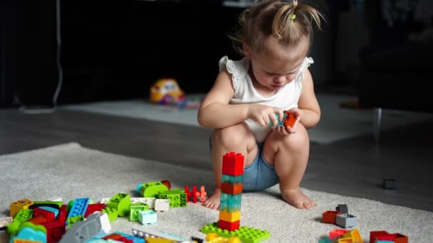 Bambino caucasico una bambina sta giocando nel costruttore a casa. Giocattoli educativi per bambini. Video al rallentatore — Video Stock