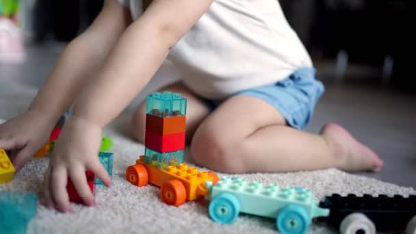 Beyaz bir çocuk evdeki inşaatçıda küçük bir kız oynuyor. Çocuklar için eğitici oyuncaklar. — Stok video