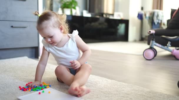 Досить маленька дівчинка грає з грибною мозаїкою для нігтів вдома. Хобі та дозвілля — стокове відео