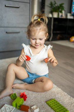 Beyaz bir çocuk evdeki inşaatçıda küçük bir kız oynuyor. Çocuklar için eğitici oyuncaklar.
