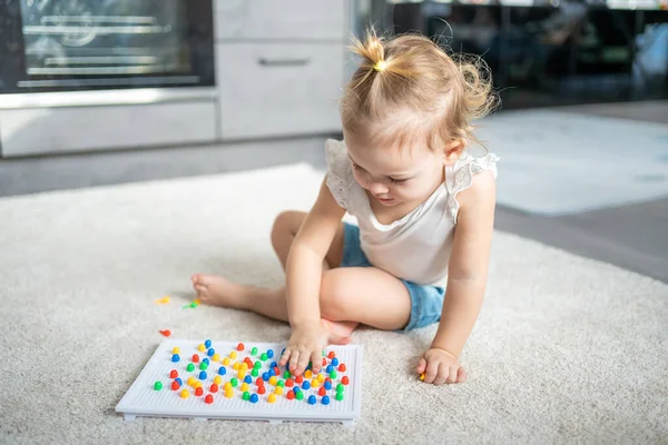 Jolie petite fille jouant avec la mosaïque d'ongles de champignons à la maison. Hobby et temps libre — Photo