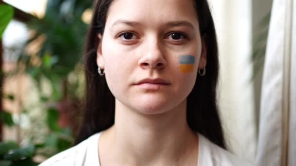 Νεαρή θλιμμένη Ουκρανή με τη σημαία της Ουκρανίας και της Ρωσίας στο πρόσωπό της κλείνει τα μάτια της. Η έννοια της συμμετοχής του ουκρανικού λαού στον πόλεμο με τη Ρωσία. Όχι πολεμική έννοια — Αρχείο Βίντεο