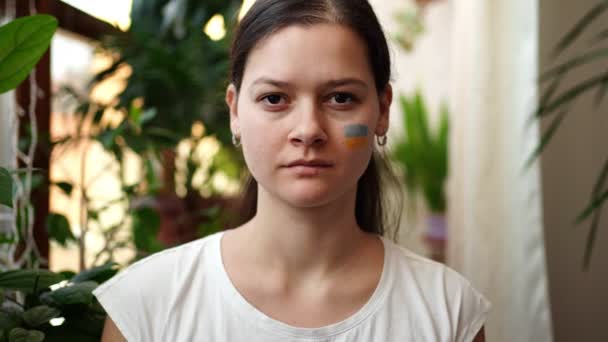 Jeune fille ukrainienne triste avec le drapeau de l'Ukraine et la Russie sur son visage ferme les yeux. Le concept de participation du peuple ukrainien à la guerre contre la Russie. Pas concept de guerre — Video