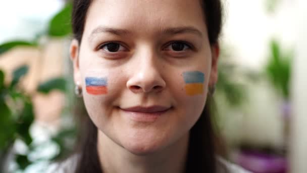 Πορτρέτο της νεαρής Ρωσο-Ουκρανής με τη σημαία της Ουκρανίας και της Ρωσίας στο πρόσωπό της. Η έννοια της συμμετοχής του ουκρανικού λαού στον πόλεμο με τη Ρωσία. Όχι πολεμική έννοια — Αρχείο Βίντεο