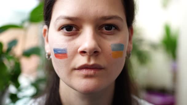 Jeune fille russo-ukrainienne avec le drapeau de l'Ukraine et la Russie sur son visage dit ARRÊTER LA GUERRE. Le concept de participation du peuple ukrainien à la guerre contre la Russie. Pas concept de guerre. — Video