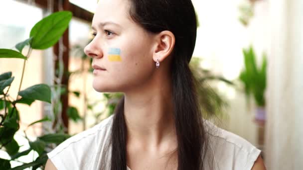 Porträtt av ung rysk-ukrainsk flicka med Ukrainas och Rysslands flagga i ansiktet. Begreppet det ukrainska folkets deltagande i kriget med Ryssland. Inte krigskoncept — Stockvideo