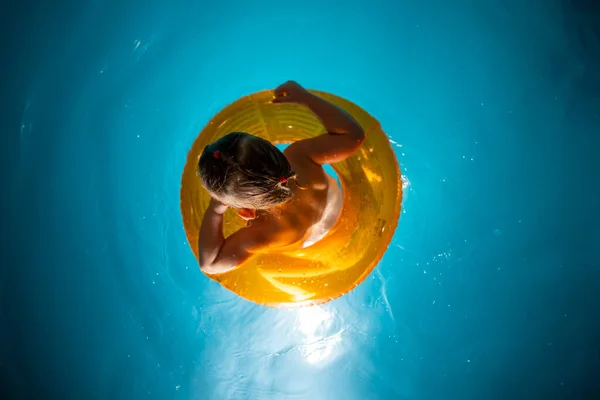 Niña en la piscina casa privada en un círculo de natación disfruta de salpicaduras —  Fotos de Stock