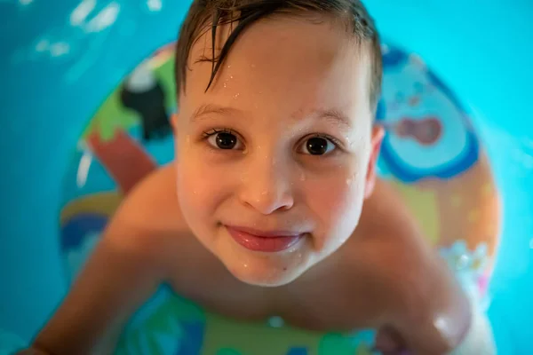 Portrait of little boy in the private home swimming pool in a blue swimming circle — Stockfoto