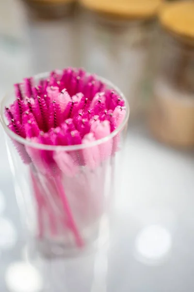 Pink eyelash brushes for eyelash extension in glass cup