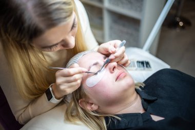 Güzellik salonunda kirpik uzatma prosedürü. Kırbaçlar yakın. Spa kirpiklerini kavra. 