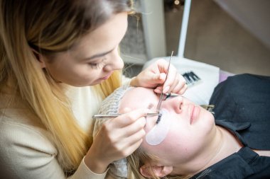 Güzellik salonunda kirpik uzatma prosedürü. Kırbaçlar yakın. Spa kirpiklerini kavra. 