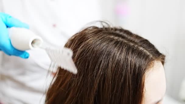 Профессиональный косметолог делает дарсонвальный уход за волосами для молодой женщины в салоне красоты — стоковое видео